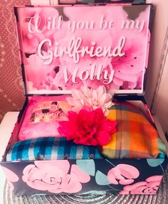 a pink flower sitting on top of a pillow in a box with the words, will you be my girlfriend money?