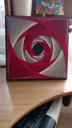 a computer keyboard sitting on top of a desk next to a red and white artwork