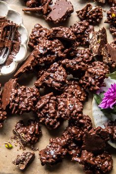 there are many pieces of chocolate on the table with flowers and spoons next to it