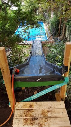 a water slide is being built in the middle of some trees and bushes with a hose attached to it