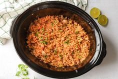 a pot filled with rice and garnished with cilantro next to sliced limes