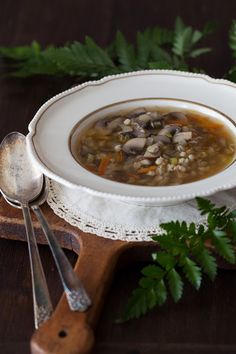 a white bowl filled with soup on top of a wooden table next to green plants