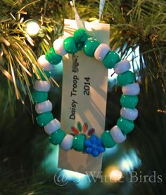 a christmas ornament hanging from a tree with green and white beads on it