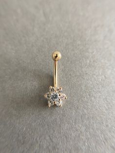 a gold nose ring with a flower design on the end and a single diamond in the middle