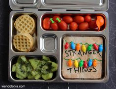 a bento box filled with fruit and veggies next to a sign that says strange things bento box