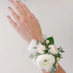 a woman's hand wearing a white wrist corsage