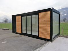 a building made out of shipping containers sitting on top of a parking lot next to a field