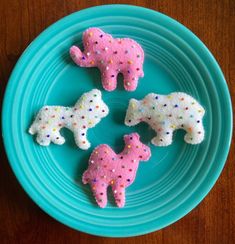 three pink and white sheep on a blue plate with sprinkles in the shape of elephants