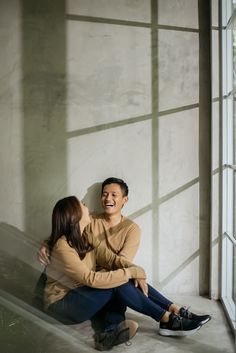 a man and woman sitting on the ground next to each other smiling at each other