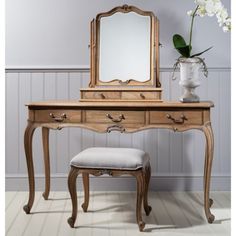 an antique dressing table with mirror and stool in the corner next to a flower vase