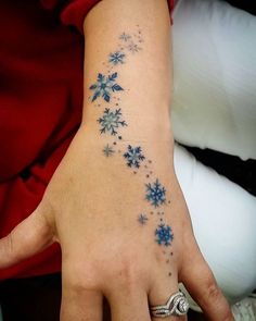 a person's hand with snowflakes tattooed on the left side of their arm