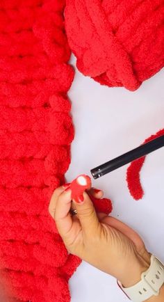 someone is making a red knitted sweater with yarn and crochet hooks on it