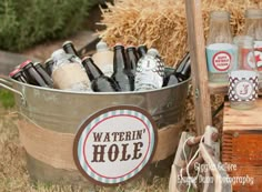 there is a bucket full of beer bottles next to two crates with straw bales in them