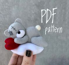 a hand holding a gray stuffed animal with a heart on it's finger and the words pdf pattern above it