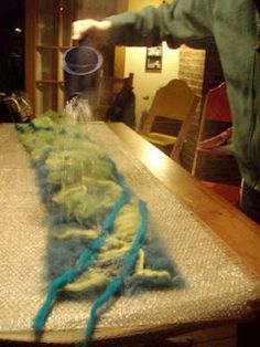 a man standing over a table with yarn on it and an object in the middle