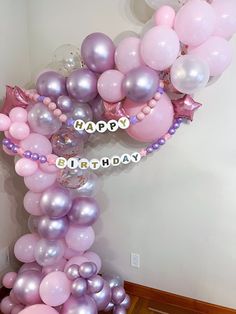 the balloon arch is decorated with pink, purple and silver balloons