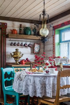 an old fashioned kitchen with tea kettles and other items on the shelves above the table