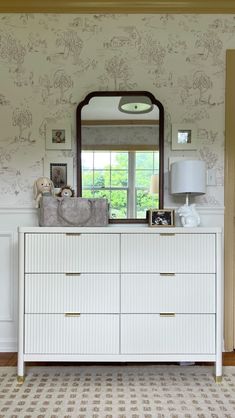 a dresser and mirror in a room with wallpaper