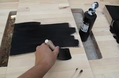 a person is painting on wood with black paint and some other things to use it