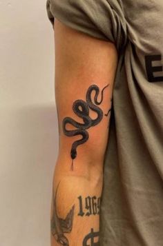 a man with a tattoo on his arm has a black snake tattooed on it's arm