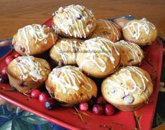 a red plate topped with muffins covered in icing and cranberries