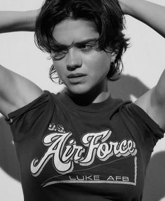 black and white photograph of a woman with her hands behind her head, wearing an air force t - shirt