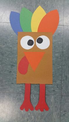 a paper cut out of a turkey with eyes and tail sitting on top of a tile floor