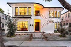 a white two story house with lots of windows on the front and side of it