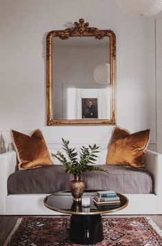 a living room filled with furniture and a large mirror above the couch, on top of a coffee table