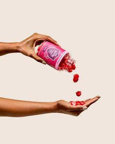 two hands reaching for a bottle of water with cherries coming out of it on a white background