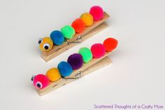 two wooden pegs with colored pom poms attached to the ends of them