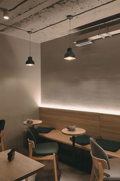 the interior of a restaurant with wooden tables and chairs, along with green cushioned seats