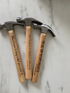 three hammers with words on them sitting on a marble counter top next to each other