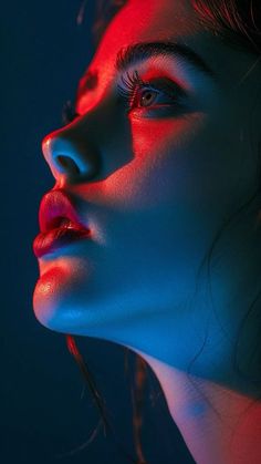 a woman with red and blue lights on her face, looking to the side while she is