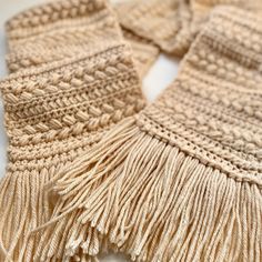 a close up of a knitted scarf with fringes on the end and one side