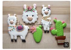 three decorated llamas and cactus cookies on top of a wooden table next to each other