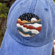 Far from the city's glare, the night sky becomes a canvas, painting dreams and stirring the soul with its timeless beauty.  Show your love for camping with this hand embroidered baseball cap! Inspired by the brilliant skies of the Rocky Mountains this cap makes a perfect gift for yourself or a loved one to commemorate a trip  or a favorite scenic view.  The hat is a high-quality, unisex, Adams Optimum Pigment Solid Dyed Twill Dad Hat in Royal Blue. The cap features a cooling mesh lining, leather strap closure, and antique brass buckle for a stylish fit. The embroidery is high quality cotton floss hand-stitched by me, and protected on the inside with interfacing. This high-quality cap will be up for many years of adventure to come! Embroidered Adjustable Baseball Cap For Outdoor, Adjustable Embroidered Outdoor Baseball Cap, Adjustable Embroidered Baseball Cap For Outdoor, Scenic View, The Rocky Mountains, Hat Embroidery, Embroidered Hat, Embroidered Baseball, Embroidered Baseball Caps