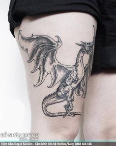 a woman's leg with a dragon tattoo on it and her legs crossed out