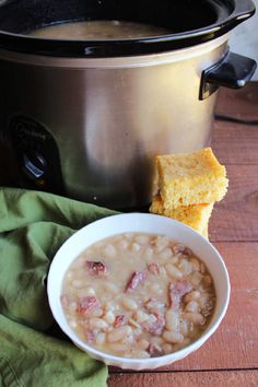 a bowl of beans and cornbreads next to an electric pressure cooker on a wooden table