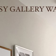 there is a sign that says easy gallery way on the wall next to two framed pictures