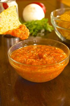 a wooden table topped with a bowl of salsa and bread