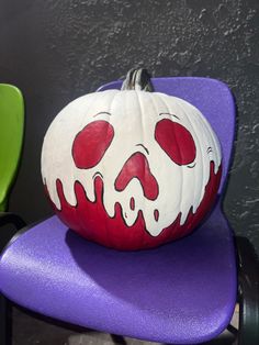 a painted pumpkin sitting on top of a purple chair