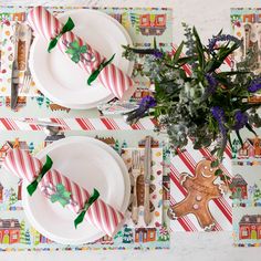 the table is set for christmas dinner with candy cane napkins