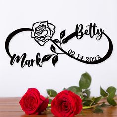 two red roses sitting on top of a table next to a metal sign that says betty mark