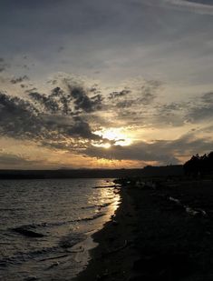 the sun is setting over the water at the beach