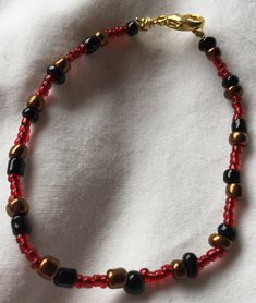 This handcrafted beaded bracelet was created using black glass beads, gold glass beads, dark red glass seed beads Red Spiritual Bracelet With Black Beads, Red Czech Glass Beaded Bracelets, Red Stretch Bracelet With Black Beads, Red Beaded Bracelets With Gold Round Beads, Red Bracelets With Black Round Beads, Diy Beaded Bracelets, Diy Jewelry Unique, Gelang Manik, Red Jewelry