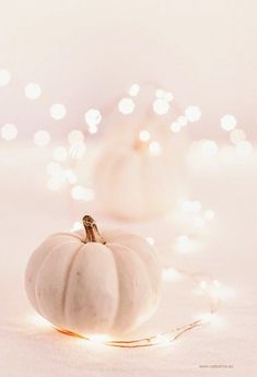 a white pumpkin sitting on top of a table next to a string of christmas lights