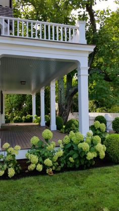 an image of a house with flowers in the front yard and bushes on the side