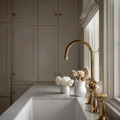 a white sink sitting under a window next to a faucet in a kitchen