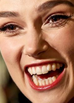 a close up of a woman smiling and holding a cell phone